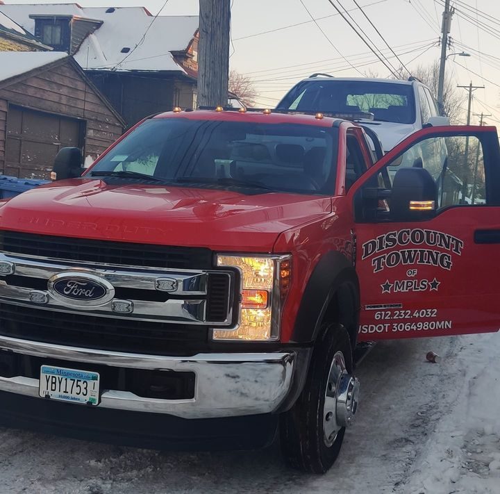 The open door of a red tow truck showing the Discount Towing of MPLS decal, the phone number 612.232.4032 and USDOT 3064980MN